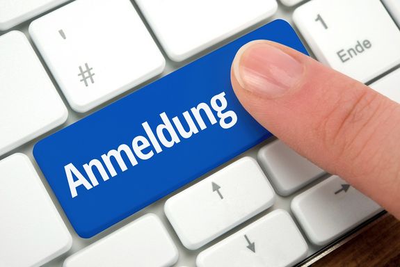 Ein Finger drückt auf eine blaue Taste mit der Beschriftung "Anmeldung".